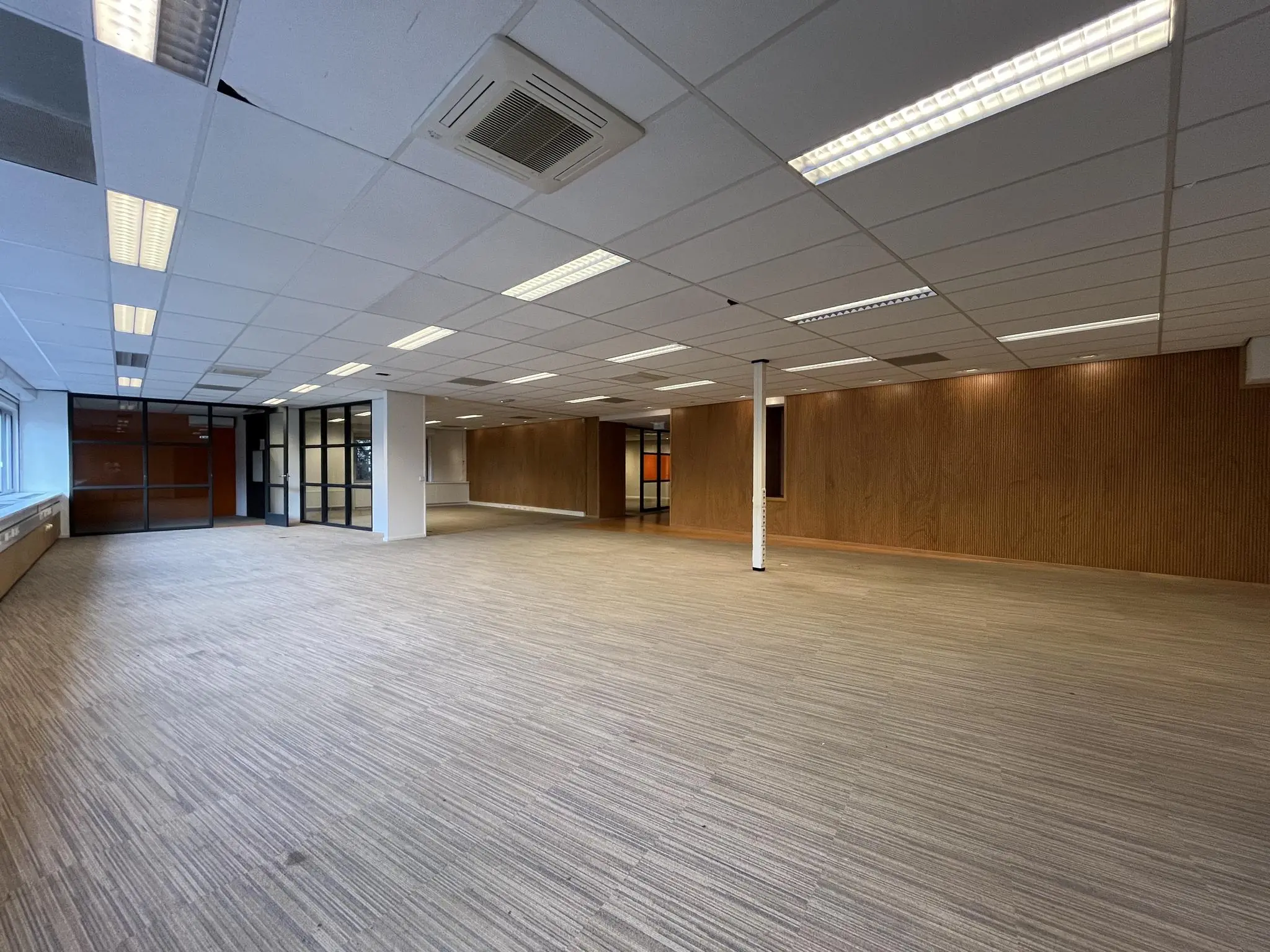 Ruime, leegstaande kantoorruimte aan de 2e Daalsedijk met systeemplafond, tapijtvloer en glazen wanden.